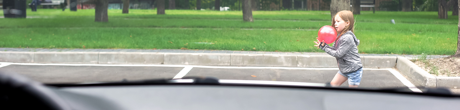 lekande barn framför bil på parkering